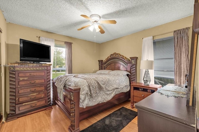 bedroom featuring light hardwood / wood-style flooring, a textured ceiling, and ceiling fan