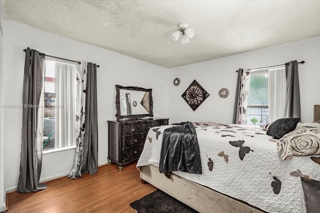 bedroom featuring light hardwood / wood-style floors, multiple windows, and a textured ceiling