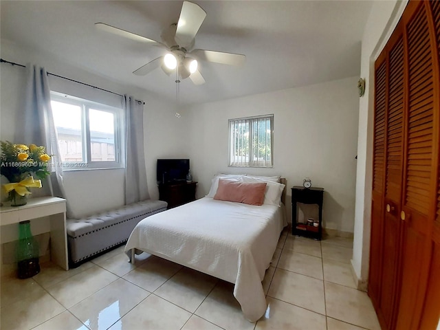 bedroom with light tile patterned flooring, ceiling fan, and a closet