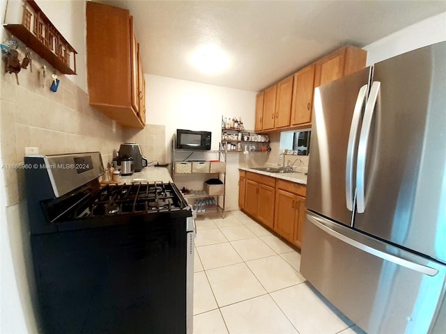 kitchen with black appliances, decorative backsplash, sink, and light tile patterned floors