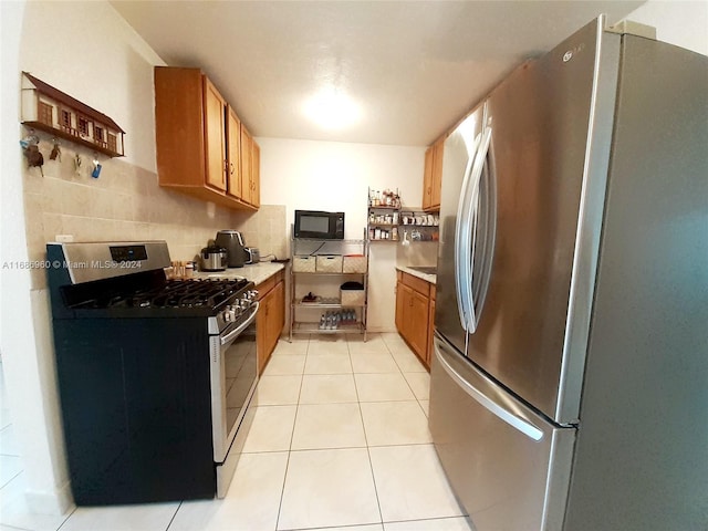 kitchen with decorative backsplash, appliances with stainless steel finishes, and light tile patterned flooring