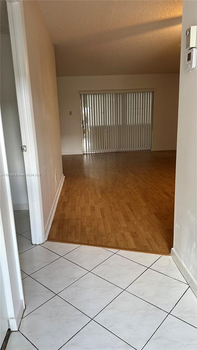 hallway with a textured ceiling and light tile patterned flooring