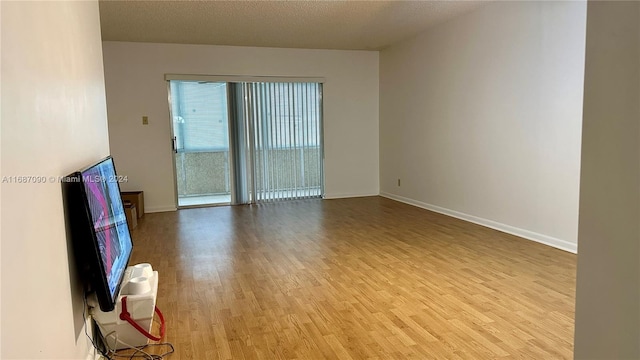 empty room with a textured ceiling and light hardwood / wood-style floors