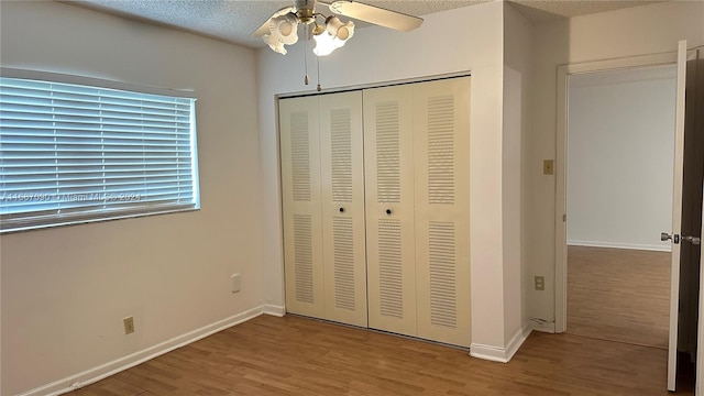 unfurnished bedroom featuring wood-type flooring, a textured ceiling, a closet, and ceiling fan