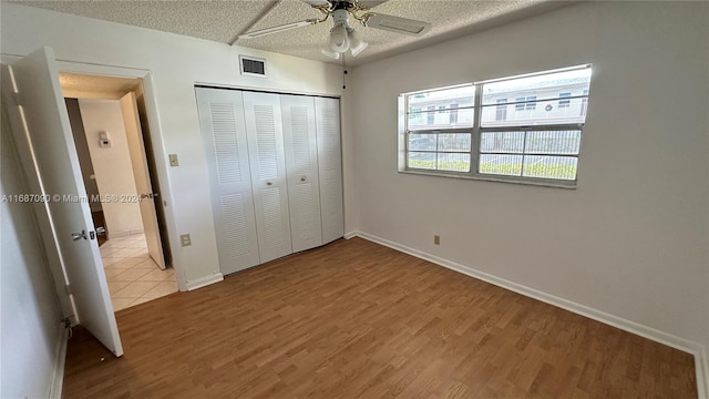 unfurnished bedroom featuring a textured ceiling, ceiling fan, light hardwood / wood-style flooring, and a closet