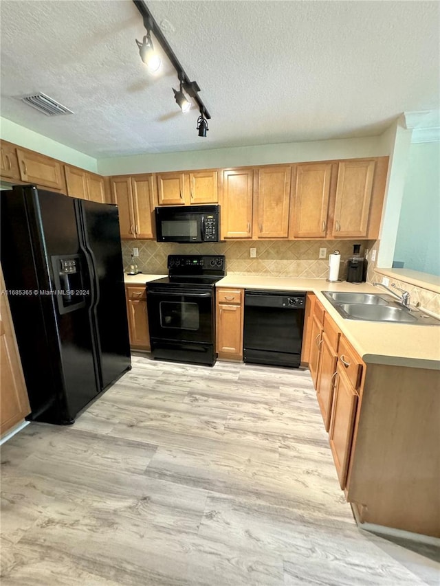 kitchen featuring sink, black appliances, a textured ceiling, and light hardwood / wood-style floors