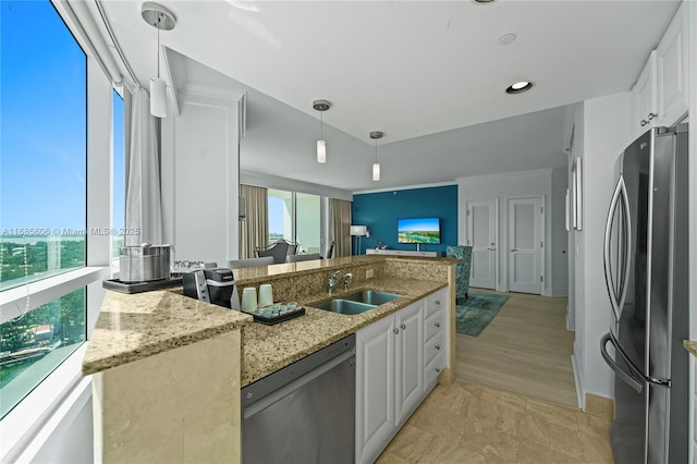 kitchen with sink, decorative light fixtures, stainless steel appliances, light stone countertops, and white cabinets