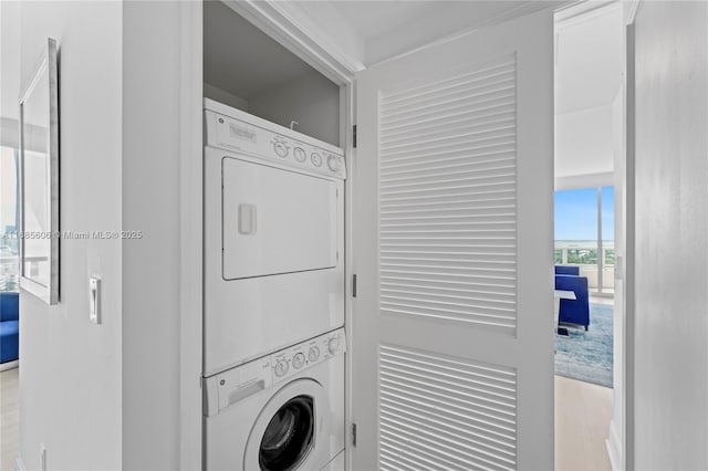 laundry room with stacked washer and clothes dryer and light hardwood / wood-style floors