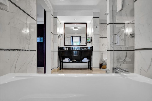 bathroom featuring vanity, a shower with door, and tile walls