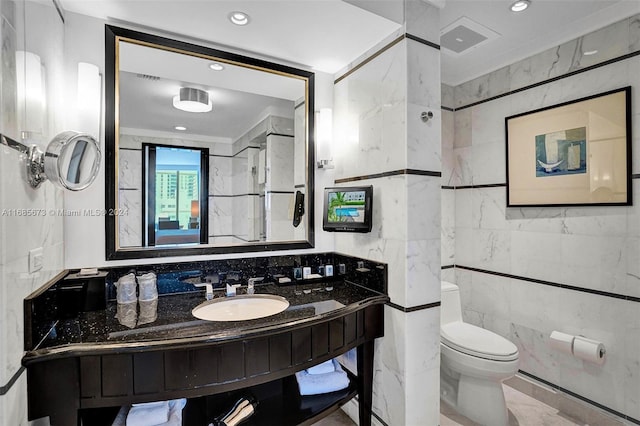 bathroom with vanity, tile walls, and toilet