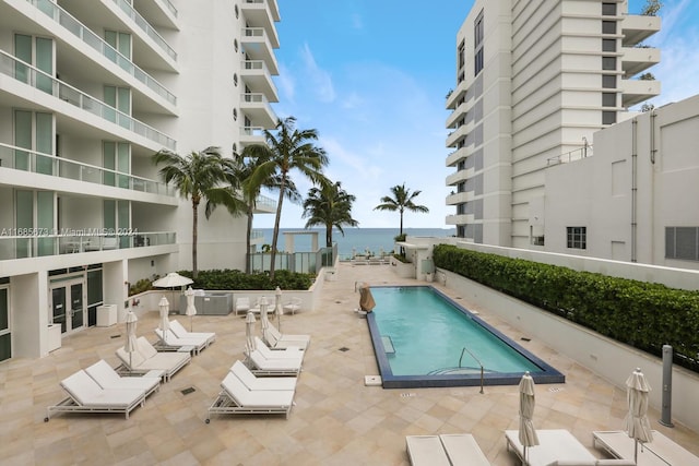 view of swimming pool with a water view and a patio area