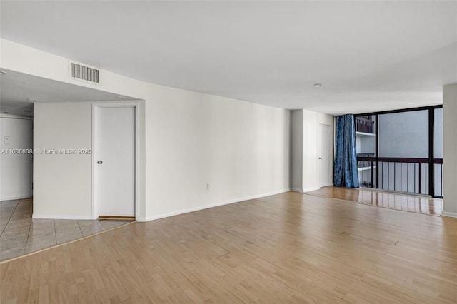 empty room featuring floor to ceiling windows and light hardwood / wood-style floors