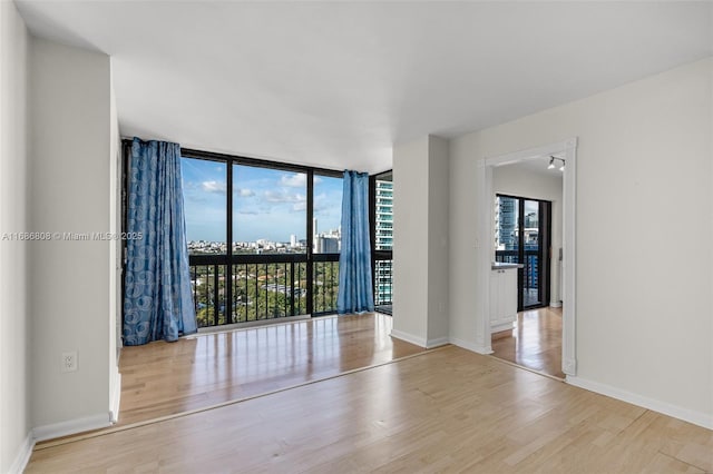 unfurnished room with floor to ceiling windows and light hardwood / wood-style floors