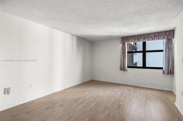 unfurnished room with a textured ceiling and light hardwood / wood-style flooring