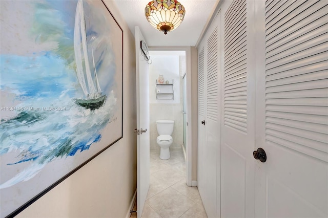 corridor with a textured ceiling and light tile patterned flooring