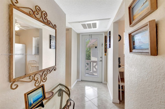 tiled foyer entrance with a textured ceiling and ceiling fan