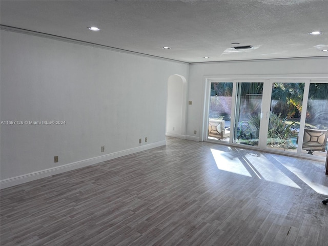 empty room with a textured ceiling, dark hardwood / wood-style floors, and ornamental molding