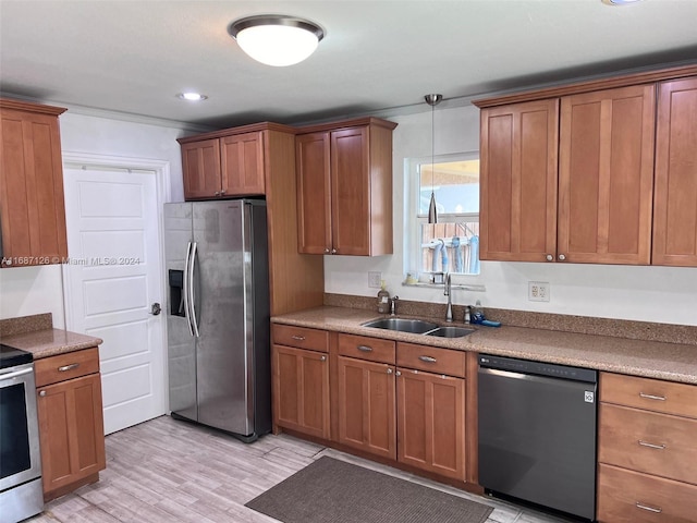 kitchen with pendant lighting, light hardwood / wood-style floors, sink, and stainless steel appliances