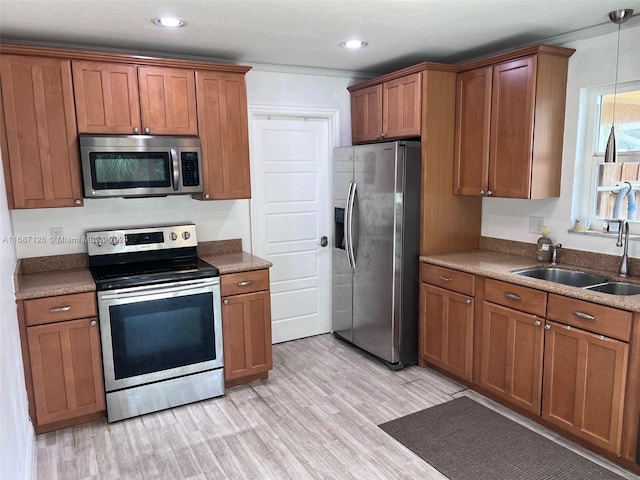 kitchen with sink, light hardwood / wood-style flooring, hanging light fixtures, and appliances with stainless steel finishes