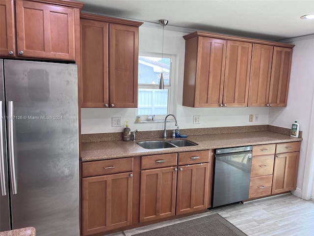 kitchen featuring hanging light fixtures, crown molding, sink, light wood-type flooring, and appliances with stainless steel finishes