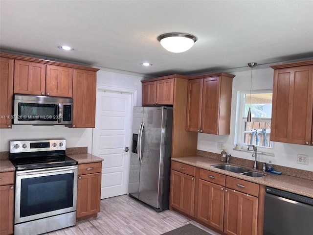 kitchen with pendant lighting, sink, light hardwood / wood-style floors, and appliances with stainless steel finishes