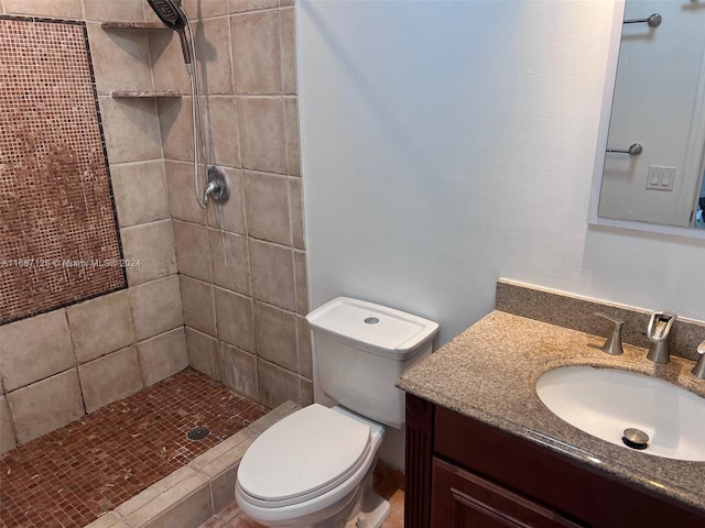 bathroom featuring tiled shower, vanity, and toilet