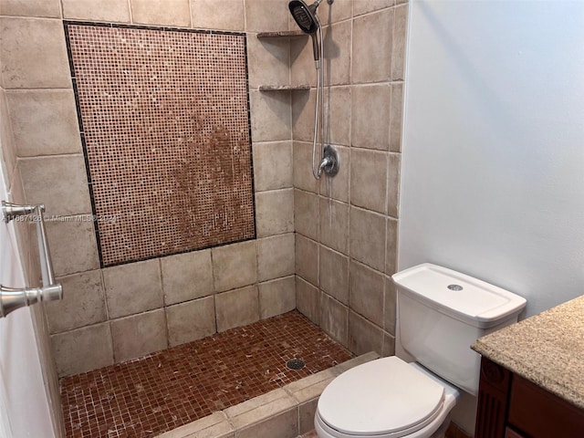 bathroom with tiled shower, vanity, and toilet