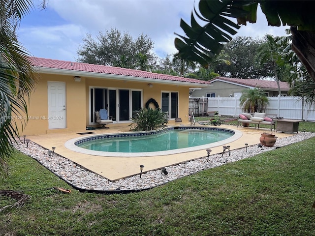 rear view of house featuring a patio, a fenced in pool, and a lawn