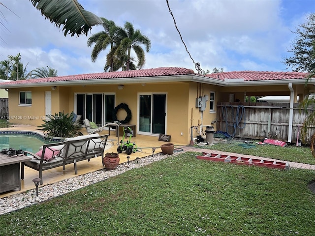 back of property with a lawn, a patio area, and a fenced in pool