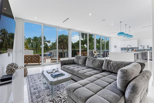 tiled living room with a wealth of natural light, sink, and a wall of windows