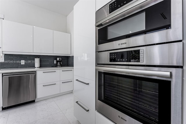 kitchen with decorative backsplash, white cabinets, and stainless steel appliances