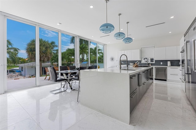 kitchen with sink, hanging light fixtures, stainless steel dishwasher, an island with sink, and white cabinets