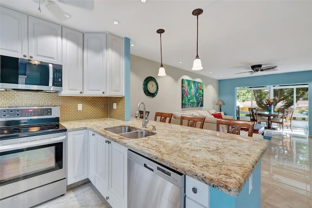 kitchen with stainless steel appliances, tasteful backsplash, a ceiling fan, a sink, and a peninsula