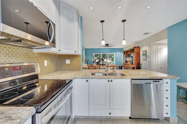 kitchen featuring light stone counters, stainless steel appliances, a peninsula, a sink, and white cabinetry