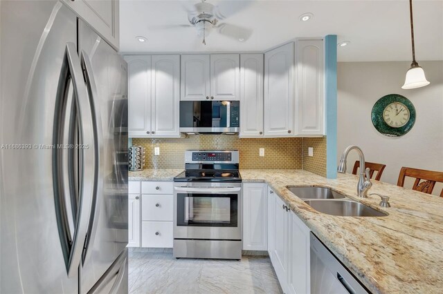 kitchen with stainless steel appliances, kitchen peninsula, sink, white cabinetry, and decorative light fixtures