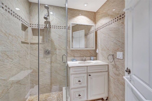 bathroom featuring tile walls, vanity, and a shower with shower door