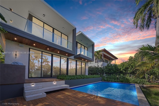 pool at dusk featuring a wooden deck