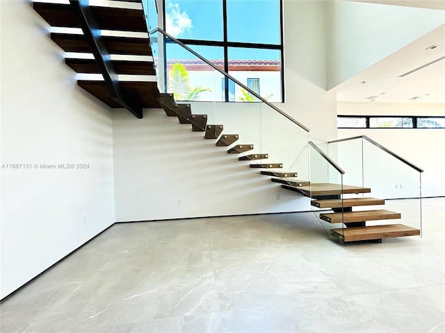 stairway featuring a towering ceiling