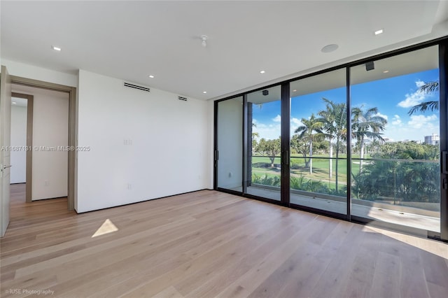 unfurnished room featuring expansive windows and light hardwood / wood-style floors