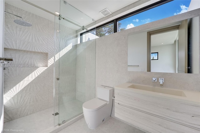 bathroom featuring vanity, a shower with door, tile walls, and toilet