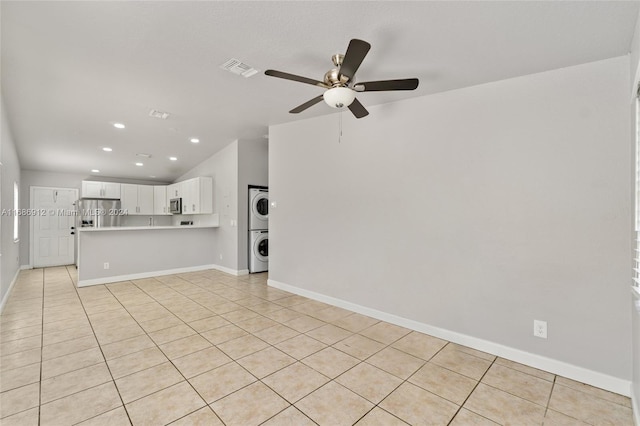 unfurnished living room featuring vaulted ceiling, ceiling fan, stacked washer and clothes dryer, and light tile patterned flooring