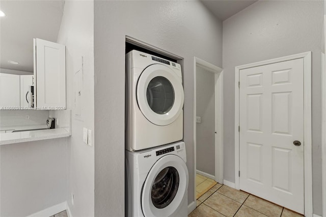 laundry area featuring light tile patterned flooring and stacked washing maching and dryer