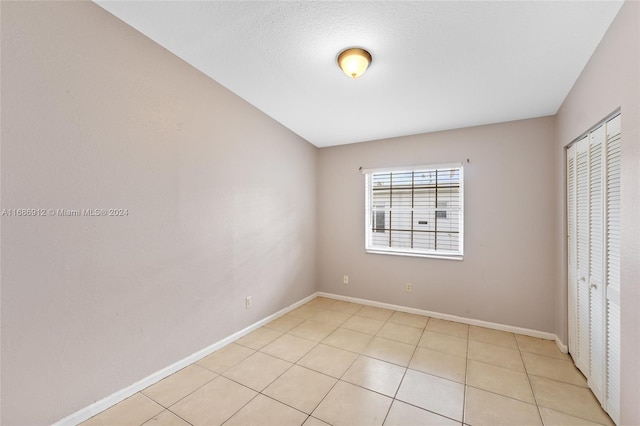 unfurnished bedroom featuring light tile patterned floors, a textured ceiling, and a closet