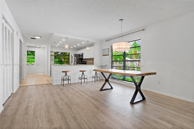 playroom featuring a chandelier, light wood-type flooring, and a textured ceiling