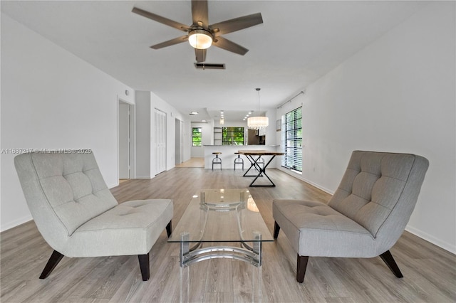 living area with ceiling fan and light hardwood / wood-style floors