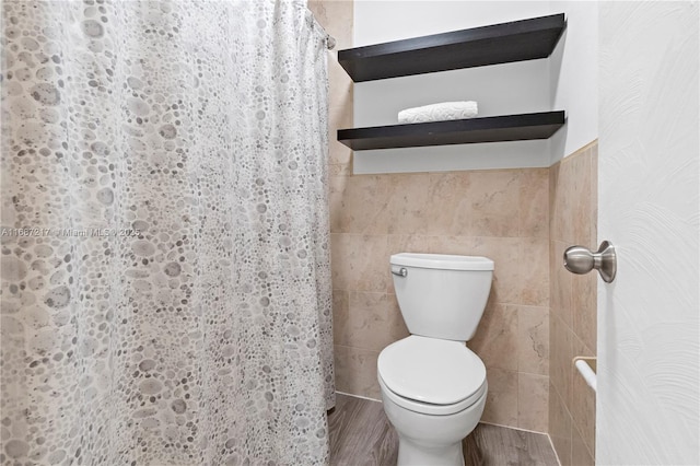 bathroom featuring wood-type flooring, toilet, walk in shower, and tile walls