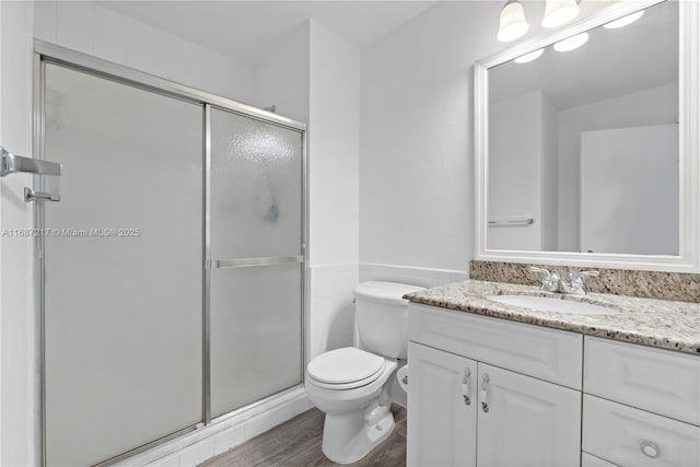 bathroom with hardwood / wood-style floors, vanity, an enclosed shower, and toilet