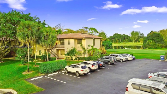 view of parking / parking lot featuring a water view and a yard