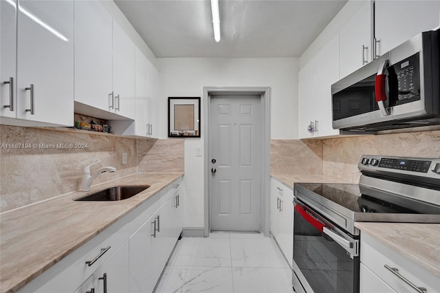 kitchen featuring sink, white cabinets, stainless steel appliances, and tasteful backsplash