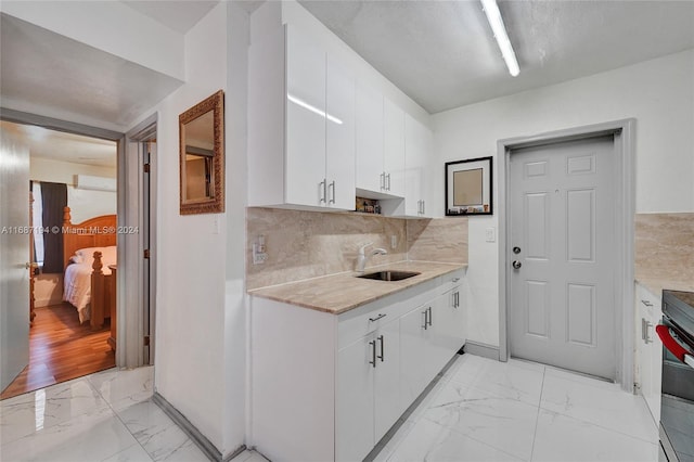 kitchen featuring light hardwood / wood-style flooring, decorative backsplash, sink, and white cabinets